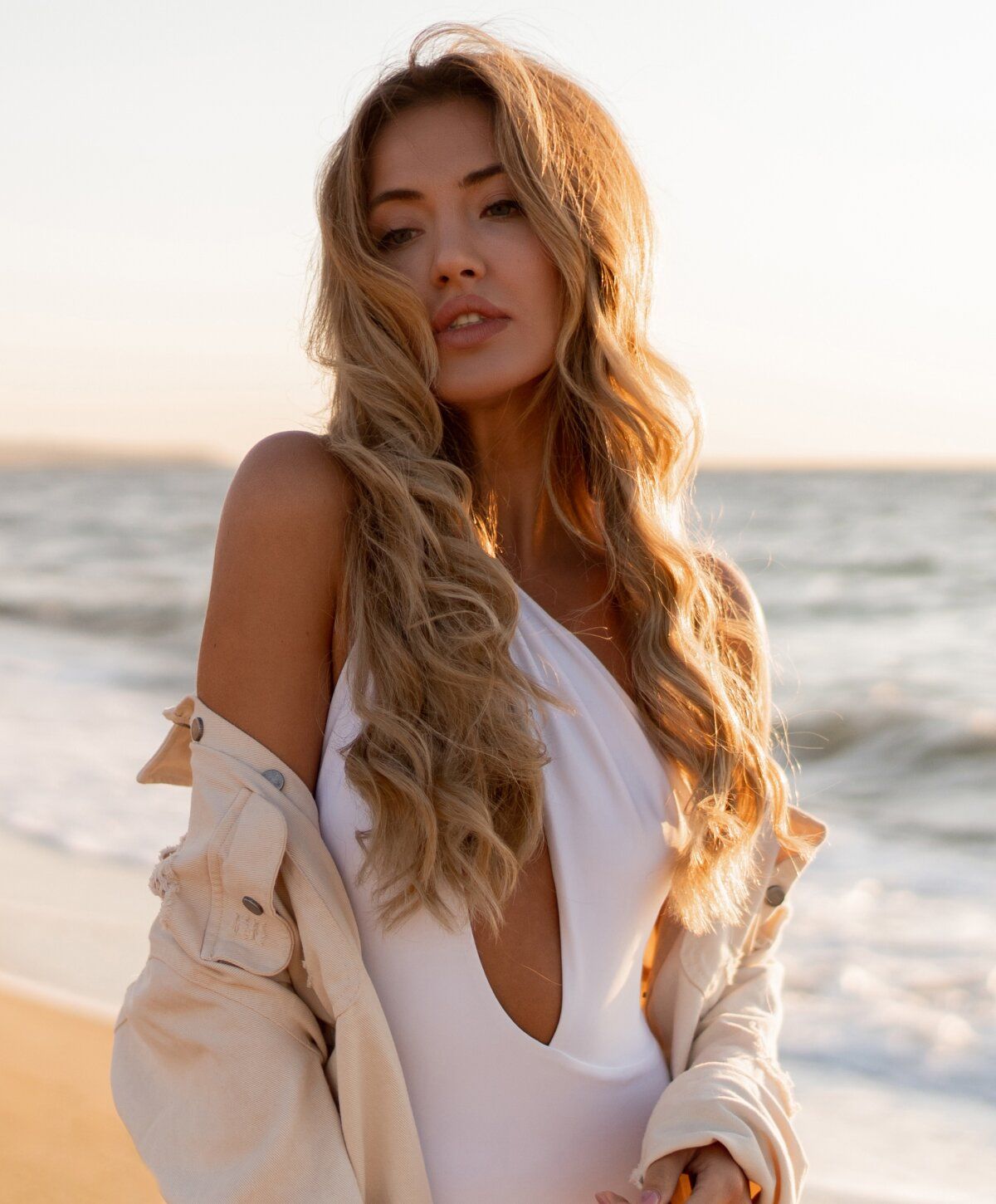 Woman in swimsuit on beach at sunset.