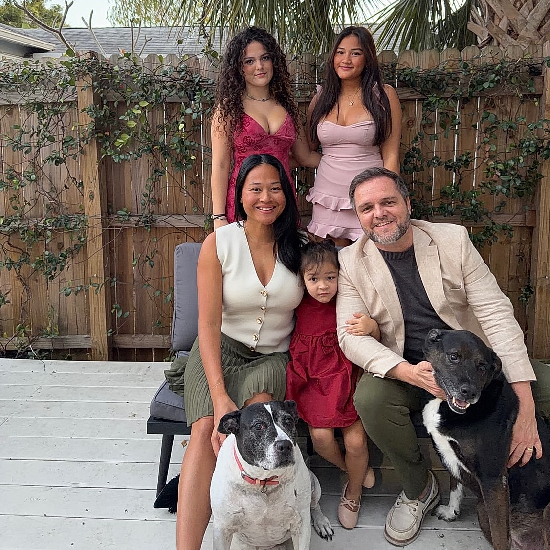 Family portrait with dogs in a backyard setting.