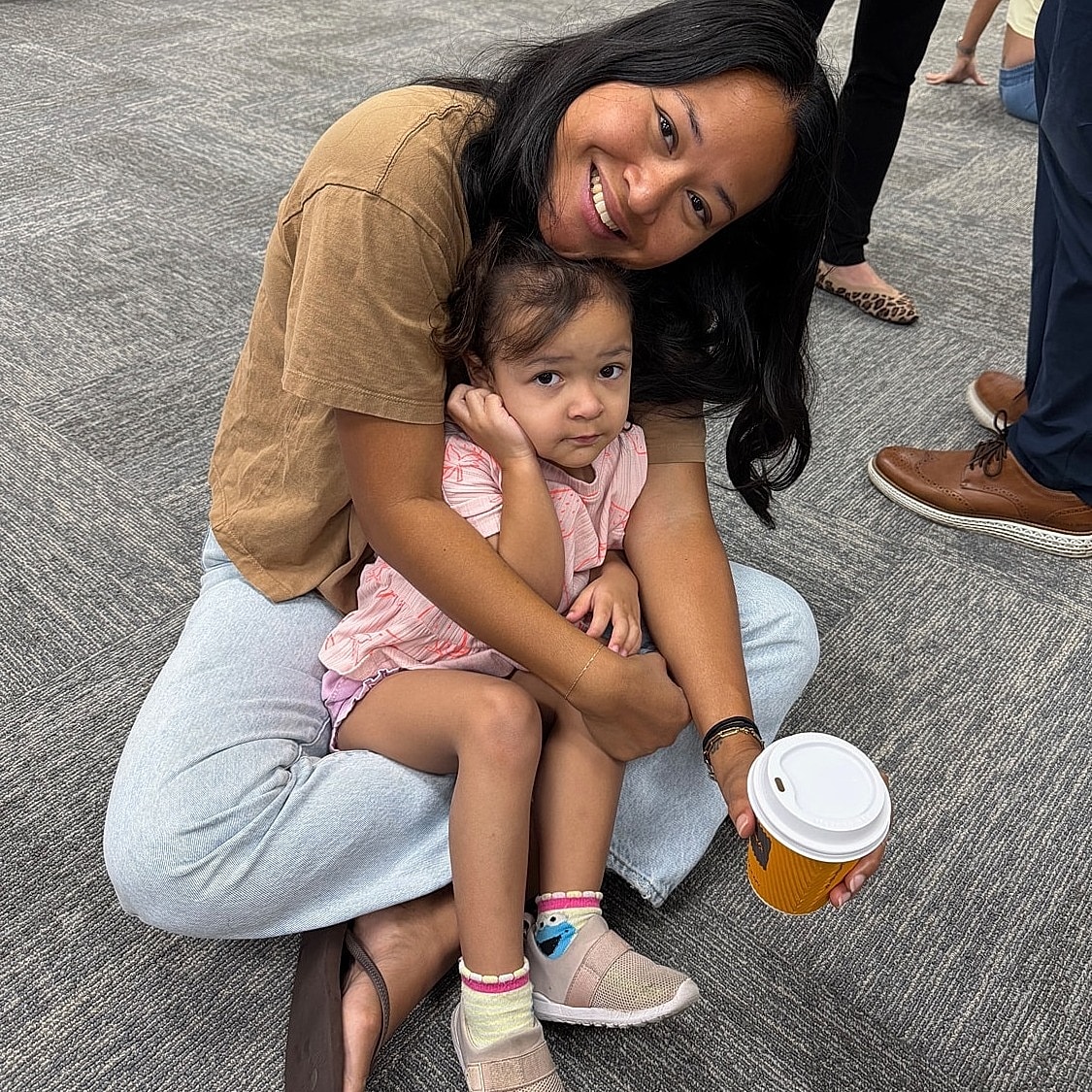 Woman holding a child, both smiling happily.