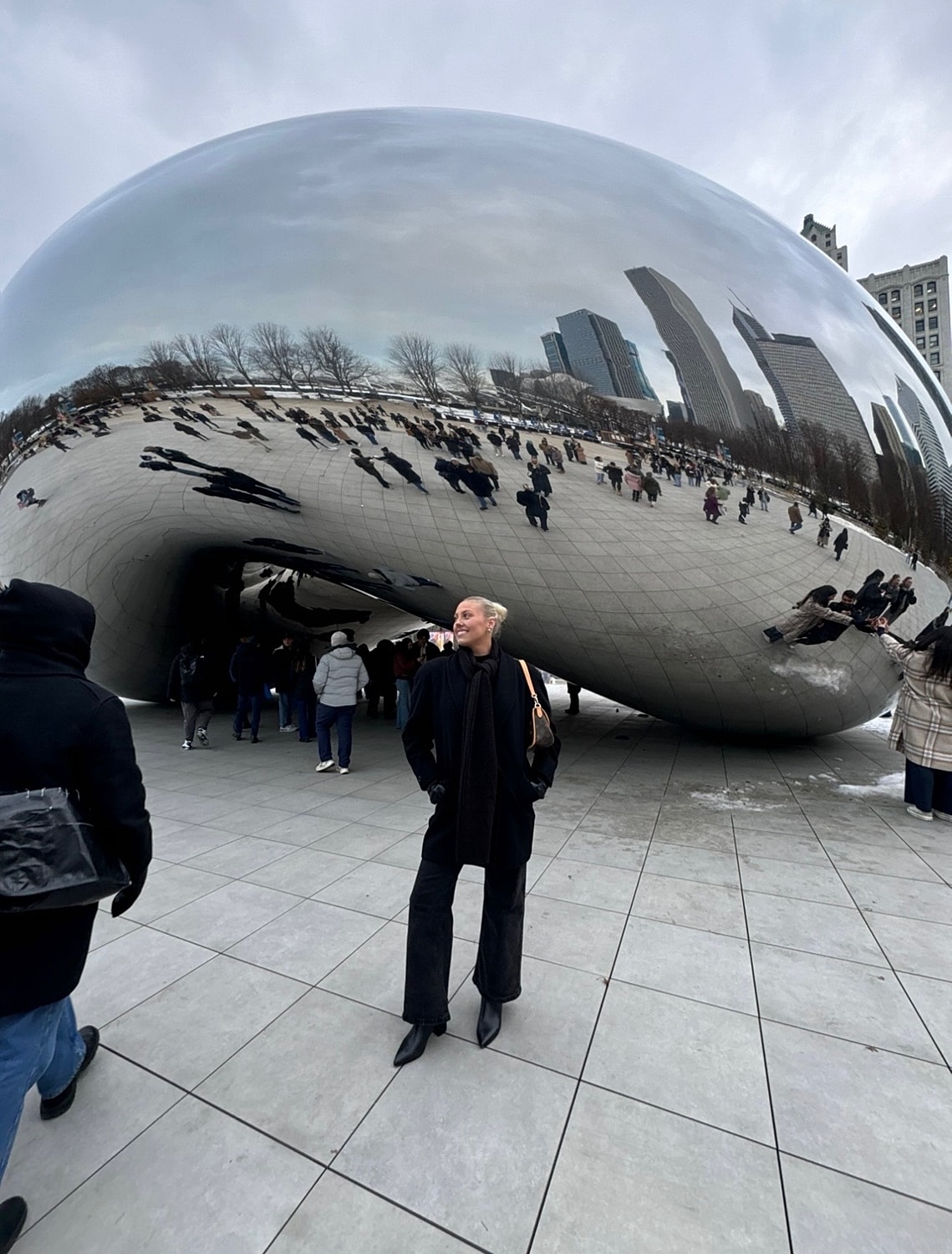 Person admiring reflective sculpture in urban setting.