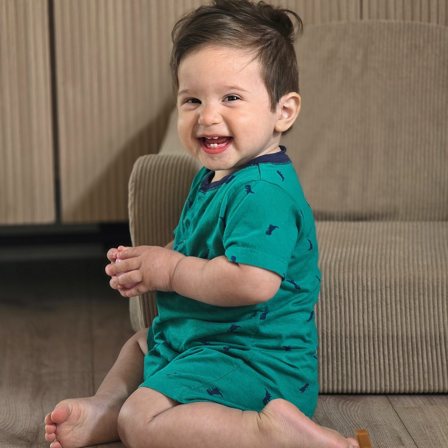 Happy baby sitting on wooden floor.