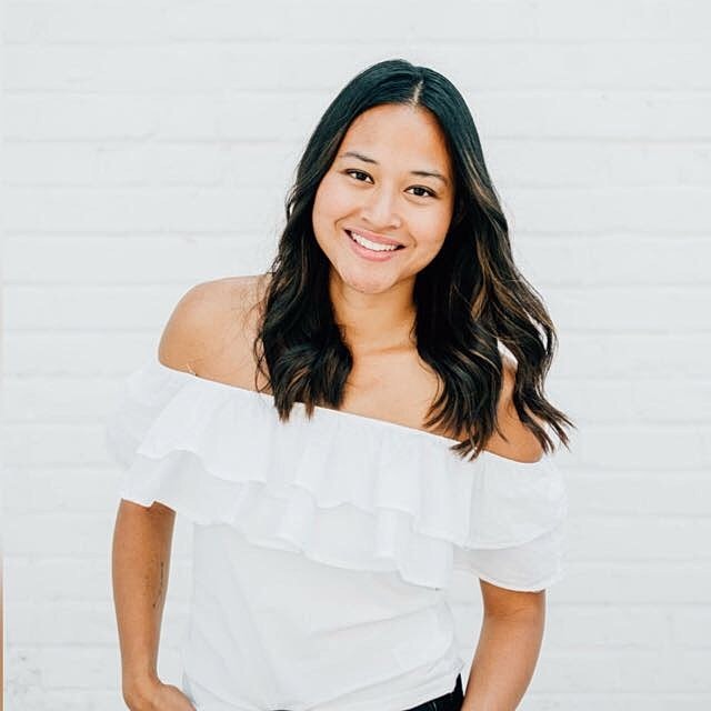 Smiling woman in off-the-shoulder white top.