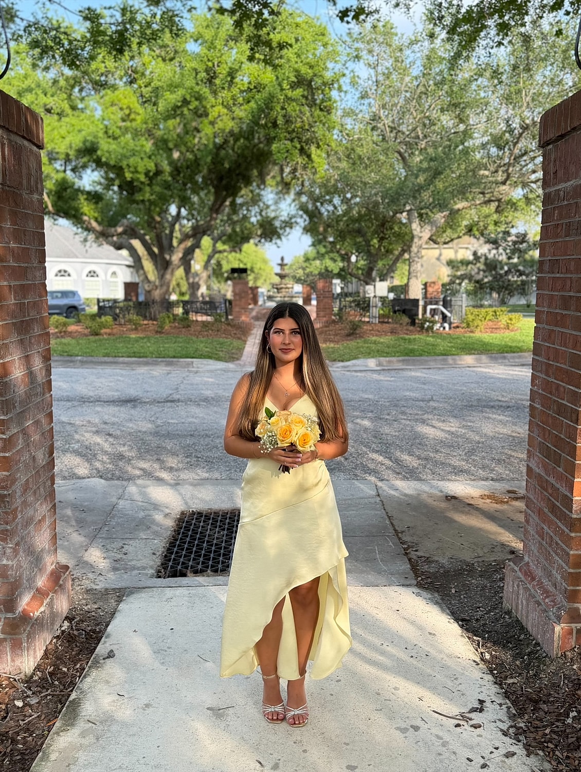 Woman in yellow dress holding bouquet outdoors.