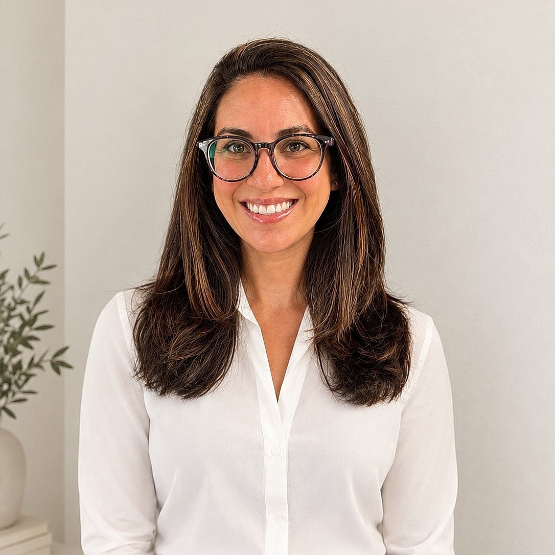 Smiling woman in professional attire against neutral background.