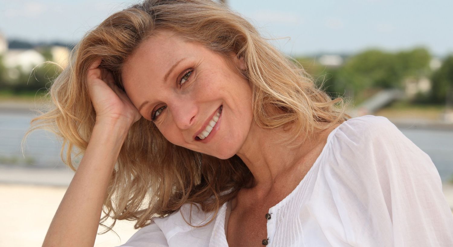 Smiling woman with flowing hair outdoors.